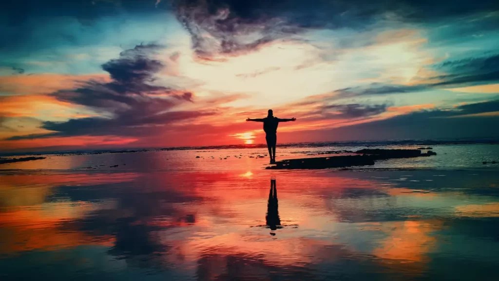 man standing in sunset spreading his hands