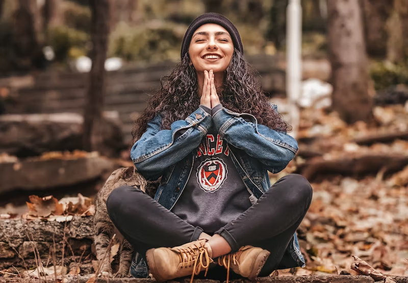 brown hair girl praying with smile in the autumn forest