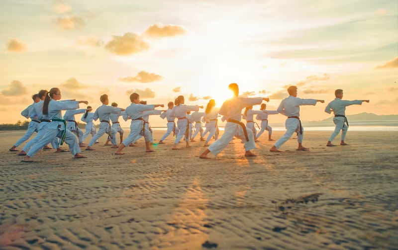 group of people on the beach practicing thai chi